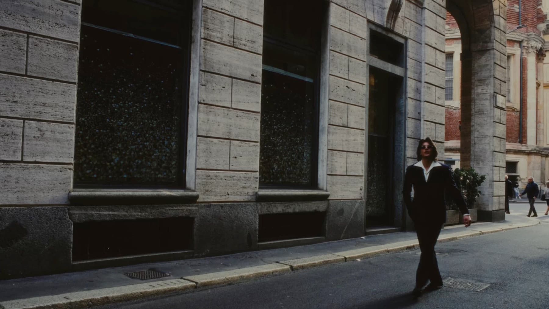 A cinematic Milano campaign scene with a suited character
